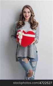 Girl with red heart-shaped box. Young girl with red heart-shaped gift box on white background