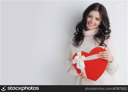 Girl with red heart-shaped box. Young girl with red heart-shaped gift box on white background