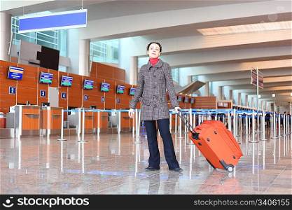 girl with red suitcase standing in airport hall