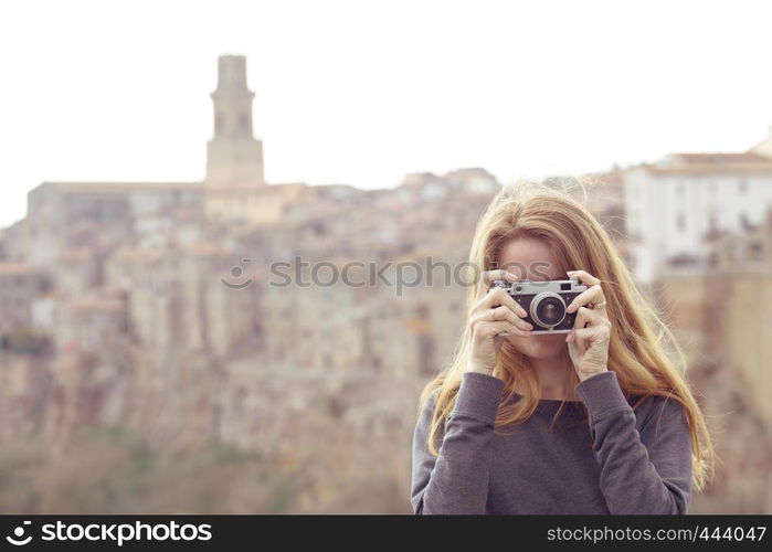 Girl with retro camera talking pictures outdoors, Italy, Pitigliano. Tuscany