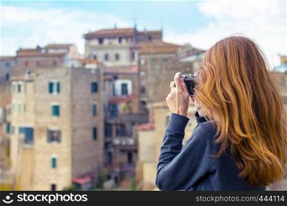 Girl with retro camera talking pictures outdoors, Italy, Pitigliano. Tuscany