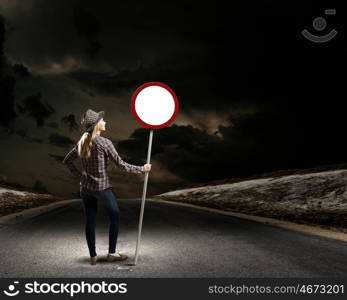 Girl with roadsign. Young woman in casual holding road sign