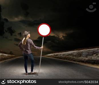 Girl with roadsign. Young woman in casual holding road sign