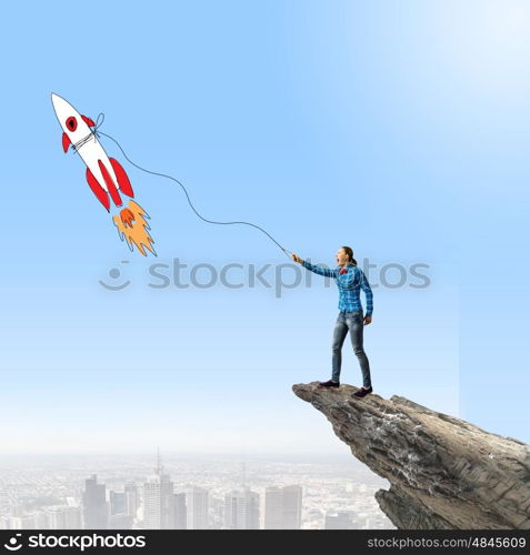 Girl with rocket. Young girl in casual and rocket flying in sky