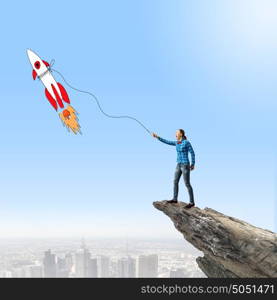 Girl with rocket. Young girl in casual and rocket flying in sky