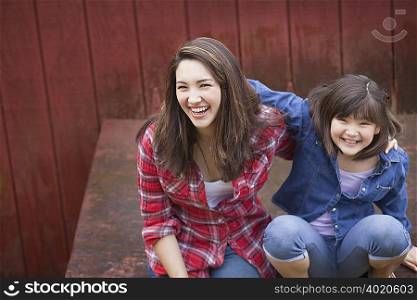 Girl with sister sitting by barn