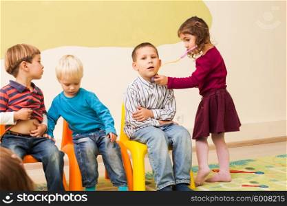 Girl with stethoscope is playing in a doctor and listening the boy&amp;#39;s belly