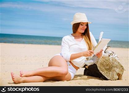 Girl with tablet on seaside.. Technology enjoyment. Long haired beauty girl in straw hat with tablet e-book on beach. Student woman resting in summer on fresh air.