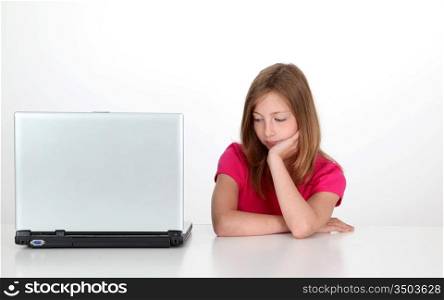 Girl with thoughtful look next to laptop computer