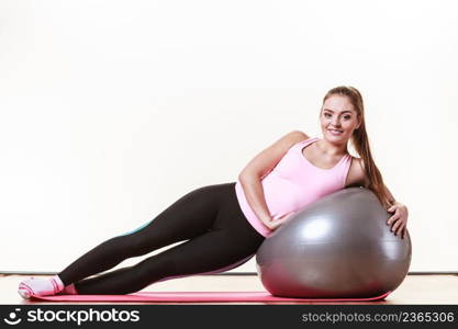 Girl with training equipment. Young female in gym with fit ball. Activity fitness health workout concept.. Girl exercising with fit ball