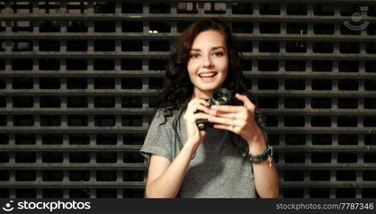 Girl with vintage camera in front of grid smiling, copyspace. Girl with vintage camera in front of grid