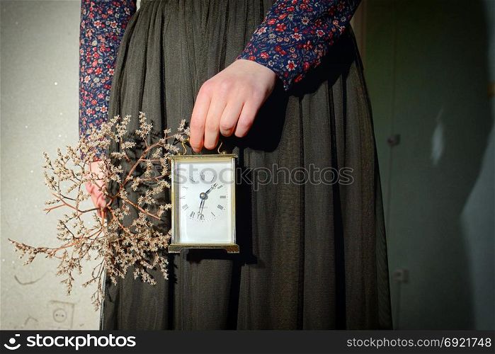 Girl with vintage dress holding clock in hand