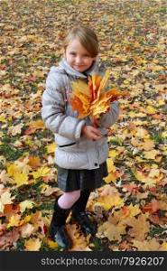 girl with yellow leaves standing in the park