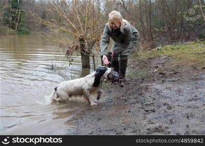 Girl working her spaniel, across water, on a shoot