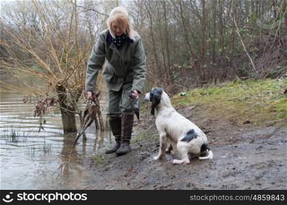 Girl working her spaniel, across water, on a shoot