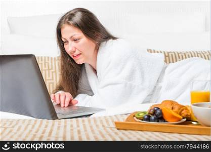 girl working on a computer in bed in the morning