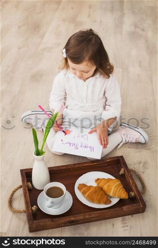 girl writing happy mothers day near tray with coffee