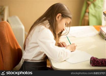 Girl writing in notebook with pencil at her bedroom