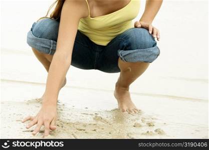 Girl writing in sand with her finger