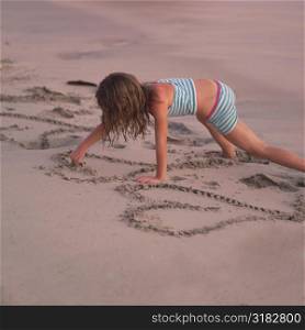 Girl writing in the sand on beach in Costa Rica