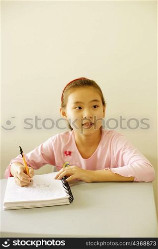 Girl writing on a spiral notebook in the classroom