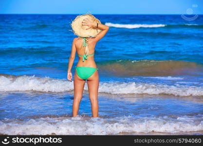 Girl young standing looking at the sea with beach hat rear back view