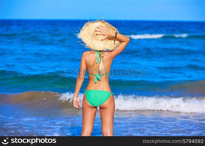 Girl young standing looking at the sea with beach hat rear back view