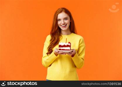 Girlfriend made surprise party, bring piece of cake with one candle to celebrate partner birthday, singing happy b-day and smiling lovely, standing orange background in yellow sweater.. Girlfriend made surprise party, bring piece of cake with one candle to celebrate partner birthday, singing happy b-day and smiling lovely, standing orange background in yellow sweater