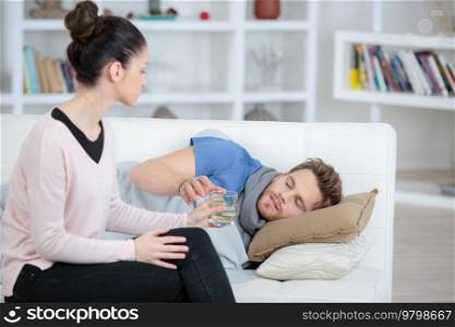 girlfriend taking care of young man on couch