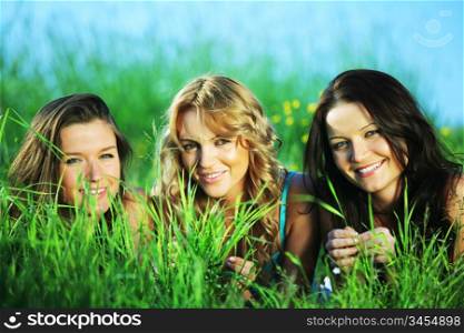 girlfriends lays on green grass and smile