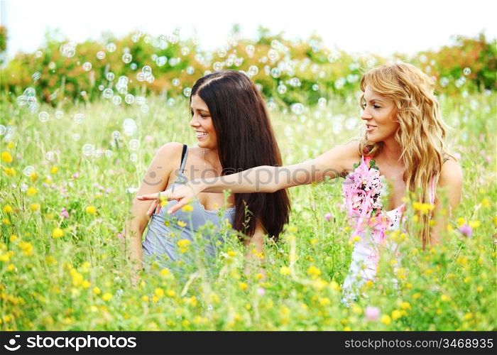 girlfriends on green grass field in soap bubbles