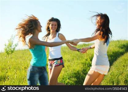 girlfriends round dance on a green grassy field