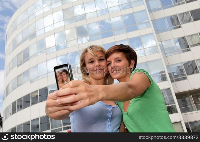 Girlfriends taking picture of themselves with mobile phone