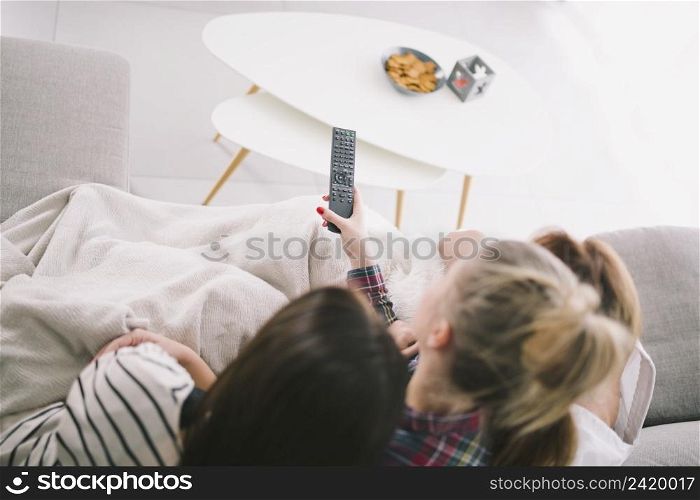 girlfriends watching tv cuddling sofa
