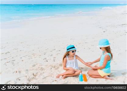Girls applying sunscreen to each other on the beach. The concept of protection from ultraviolet radiation. UV protection. Sister puts sunscreen on her little sister&rsquo;s nose