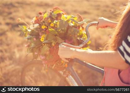 Girls arms holding an old bike handlebar with flowers basket