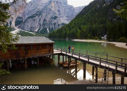 girls backpacker standing on a pier and looking at Braies lake, Dolomites Italy