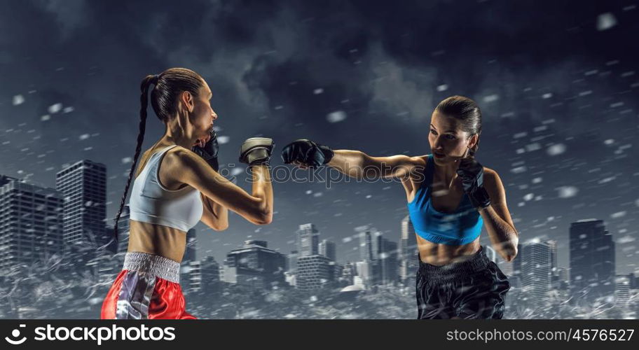 Girls boxing outdoor. Two young pretty women boxing against night city background