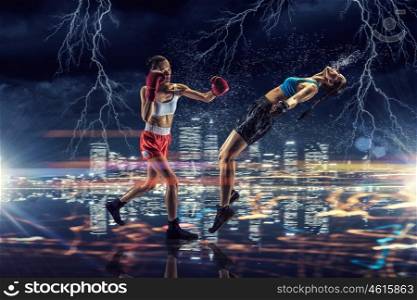 Girls boxing outdoor. Two young pretty women boxing against night city background