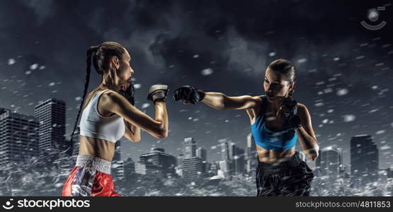 Girls boxing outdoor. Two young pretty women boxing against night city background