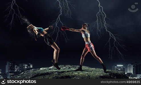 Girls boxing outdoor. Two young pretty women boxing against night city background