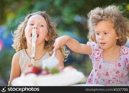 Girls cutting cake outdoors