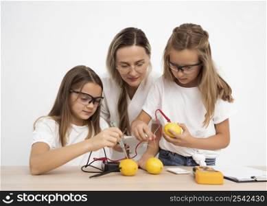 girls doing science experiments with female teacher lemons