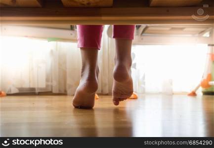 Girls feet under bed at sunny morning