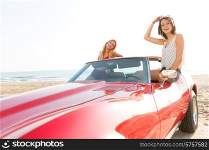 girls friends at beach in sports car convertible having fun