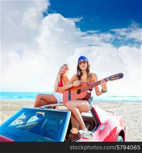 girls having fun playing guitar on th beach with a convertible car