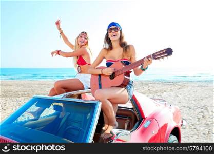 girls having fun playing guitar on th beach with a convertible car