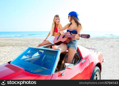 girls having fun playing guitar on th beach with a convertible car