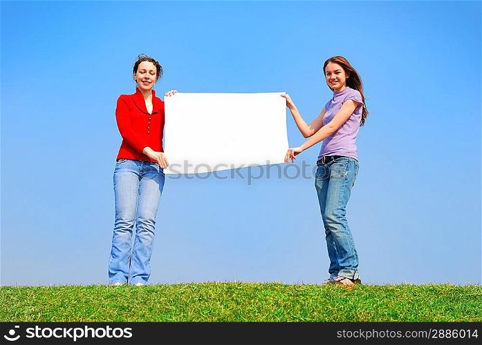 Girls holding blank sheet against blue sky