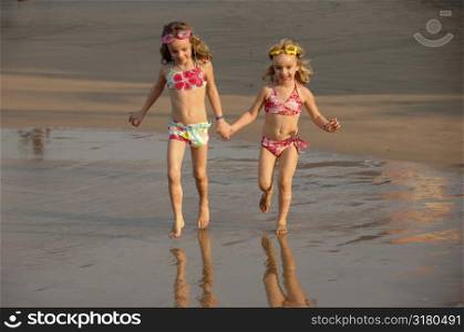 Girls holding hands running on the beach